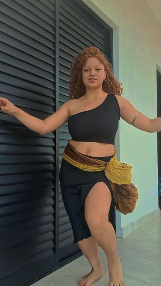 Professora de dança do ventre com lenço dourado no quadril